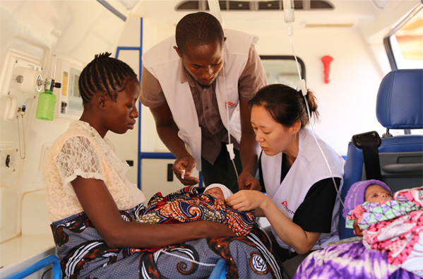 A parent holding a newborn and medical staff treating the child